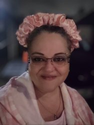girl Khobie smiles at the camera wearing a bow, eye glasses, and a pink top