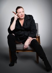 Image of seated older white woman dressed in black holding a cigar.