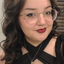 A close-up image of Nonnie, a young white woman with dark curled hair and round gold glasses. She is wearing red lipstick and smirking slightly.